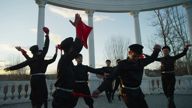 4K Group of Caucasian dancers in local black costumes perform traditional folk dance . Group of Men dancing traditional dance with handkerchief . Outdoor Shot on RED EPIC DRAGON Cinema Camera .