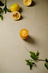 Passion fruit mocktail. Glass on old wooden table with fruits and leaves.