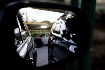 Abstract and blurred of Rear view of two cars parked in a car park in the gloomy evening light. View inside of mirror wing.