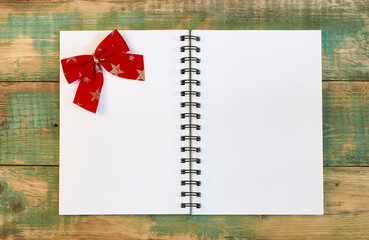  red bow on a white page of an open notebook on a wooden background