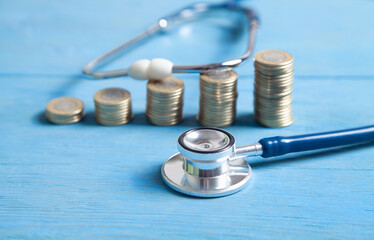 Stethoscope and coins on the blue background.
