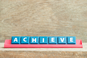 Obraz premium Tile alphabet letter with word achieve in red color rack on wood background