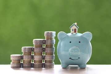 Finance and Banking, Model house on piggy bank with stack of coins money on nature green background,Business investment and real estate concept