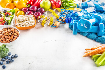 Selection of healthy foods, vegetables, fruits, almonds, salad, exercise tools and measuring tape