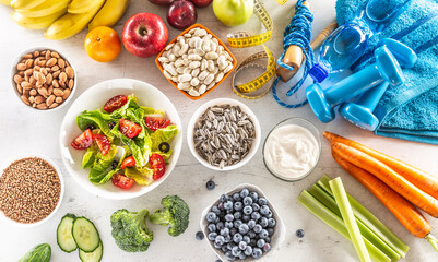 Selection of healthy foods, vegetables, fruits, almonds, salad, exercise tools and measuring tape