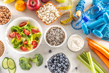Selection of healthy foods, vegetables, fruits, almonds, salad, exercise tools and measuring tape