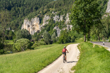 beautiful active senior woman cycling with her electric mountain bike in the rocky Upper Danube Valley on the Swabian Alb between Beuron and Sigmaringen