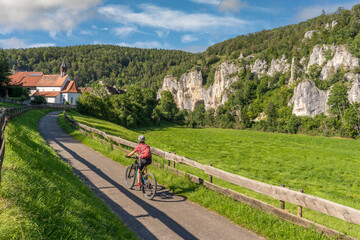 Fototapeta premium beautiful active senior woman cycling with her electric mountain bike in the rocky Upper Danube Valley on the Swabian Alb between Beuron and Sigmaringen