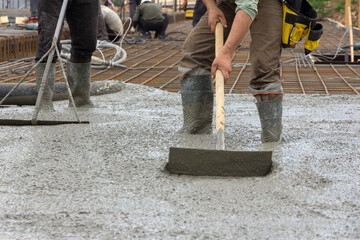 The process of pouring a monolithic slab at a construction site. Construction workers leveling wet...