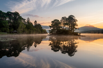 Beautiful Summer sunrise reflections on peaceful morning at Derwentwater in The Lake District, UK.