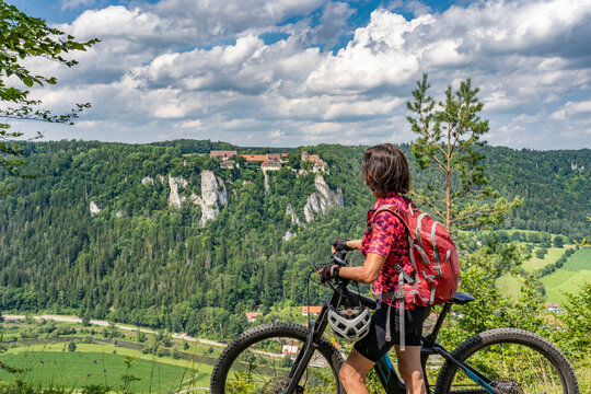 beautiful active senior woman cycling with her electric mountain bike in the rocky Upper Danube Valley on the Swabian Alb between Beuron and Sigmaringen