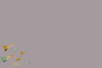 Back to school creative concept. Gold and grey paper clips and pin pattern on a purple background. Business backdrop. Top view, flat lay. Seamless image.