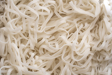 The texture of rice noodles. White noodles are visible throughout the frame. An ingredient for making a wok. Asian food. Asian pasta. Cooking food. Strid food. Gluten-free fries. Rice noodles.
