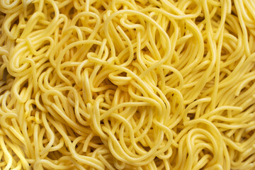 The texture of egg noodles. Yellow noodles are visible throughout the frame. An ingredient for making a wok. Asian food. Asian pasta. Cooking food. Strid food. Gluten-free fries.