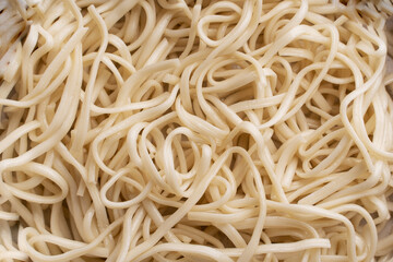 The texture of udon noodles. White noodles are visible throughout the frame. An ingredient for making a wok. Asian food. Asian pasta. Cooking food. Strid food. Gluten-free fries. 