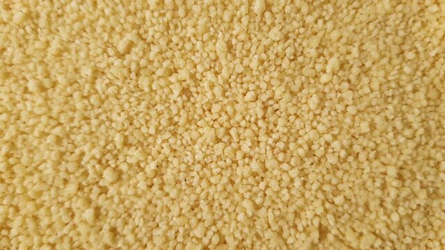 Close up of yellow golden dry couscous top view from above. Macro food us a background with copy space from above. Nutrition vegan vegetarian ingredient concept.
