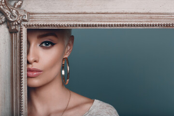 Millenial young woman with short blonde hair on gilded picture frame. Cropped face of beautiful...