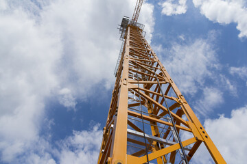 Construction crane against the blue sky. Beige crane at the construction site.