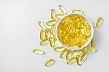 Top view of Gold fish oil in bowl isolated on white background view. Flat lay of Supplementary food. Omega 3. Vitamin E. Capsules salmon fish oil. Copy sapce.