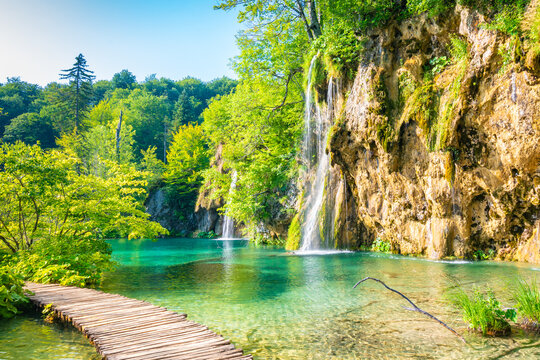 Wooden footpath at Plitvice national park, Croatia. Pathway in the forest near the lake and waterfall. Fresh beautiful nature, peaceful place. Famous tourist destination.