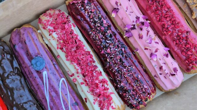 french eclairs group dessert, set with original creamy delicious colorful eclairs with nuts, berries and glaze