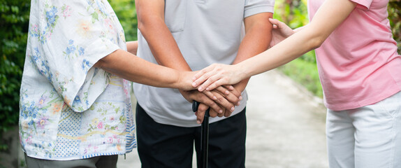 Happy family walking together in the garden. Old elderly using a walking stick to help walk balance. Concept of  Love and care of the family And health insurance for family