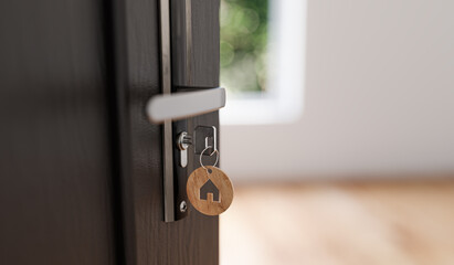 Key in the door with a house-shaped pendant. The concept of a new apartment was purchased from a developer.
