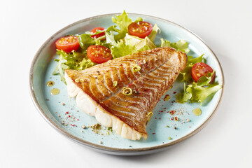 Fried fish steak with mixed leaves and cherry tomatoes