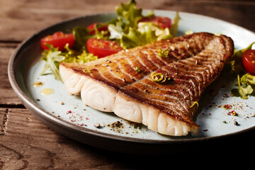 Fried fish fillet with garnish on plate