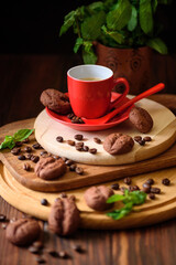 Coffee cup, beans and chocolate cookies on dark wooden table. Selective focus. Front view