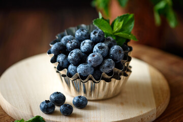 Juicy and fresh blueberries with green mint leaves on wooden table. Selective focus