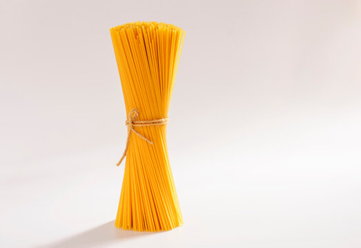 Top view of a bunch of bucatini or perciatelli - pasta, spaghetti on a white background. There was a faint sunlight coming from behind.