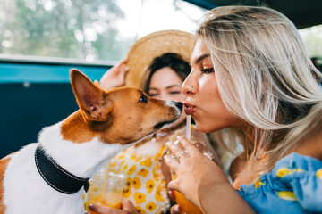 Portrait of two attractive cheerful woman sitting in a van with dog, enjoying summer vibes during road trip.