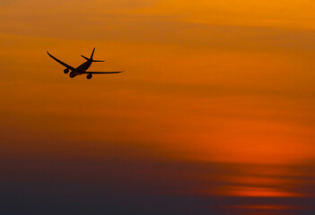 Fototapeta na wymiar The silhouette selective focus view of airliner taking off against the sunset sky in the evening