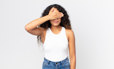 pretty hispanic woman covering eyes with one hand feeling scared or anxious, wondering or blindly...