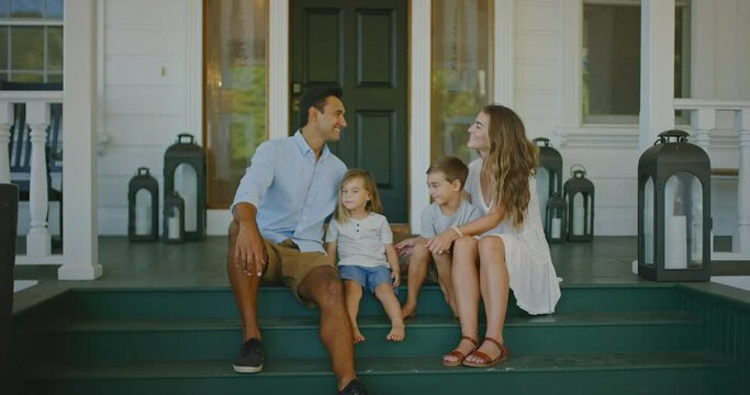 Happy diverse young family relaxing on the steps of their home smiling and laughing, family lifestyle