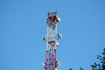 Telecommunications tower with a 5G cellular network antenna on a blue sky background.
