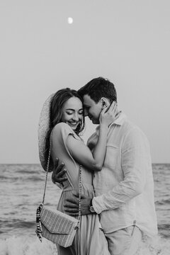 Portrait of happy young couple under the moonlight. Couple is walking along the beach. Black and white photo. High quality photo