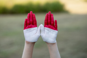 Child girl show hands painted in Indonesia and Monaco flag colors. Indonesian patriotism concept. Indonesian Independence Day, Hari Kemerdekaan Indonesia, 17 August. National Day of Monaco 19 November