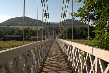 shadows on chainbridge over river Tweed and Eildon hills in summer