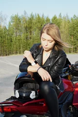 Foto op Plexiglas A girl with light brown hair and a leather jacket on a red motorcycle wearing a helmet.She enjoys the summer sun and life. © Полина Викторовна