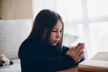 Girl praying with hands on bible. Concept for faith,spirituality and religion.