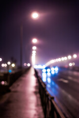 The bright lights of the city at night, busy traffic on the road bridge. Defocused image