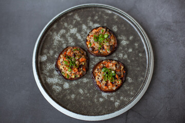 Eggplants baked with vegetables on a black plate