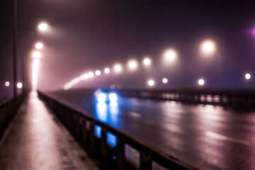The bright lights of the city at night, the car goes over the road bridge. Defocused image