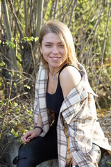 Smiling girl with light brown hair and a checkered shirt, sunny warm day.
