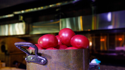 tomato in a saucepan, muted dark background
