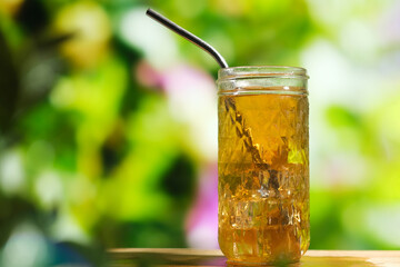Glass of ice tea with lime in summer garden. Healthy refreshing summer beverage outdoors.