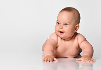 Happy portrait Six month old baby girl in a diaper lying and looking with interest to the side on a white background