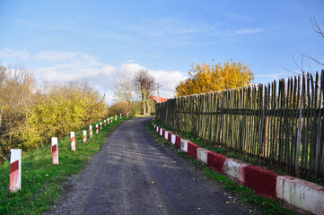 Empty village road among traditional wooden fence  - 448809272